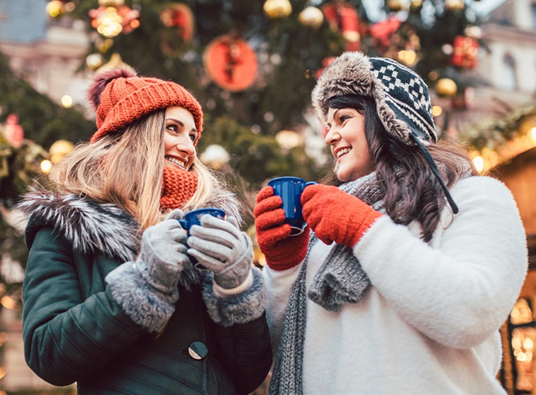 Két barátnő meleg italokat iszik a szabadban télen